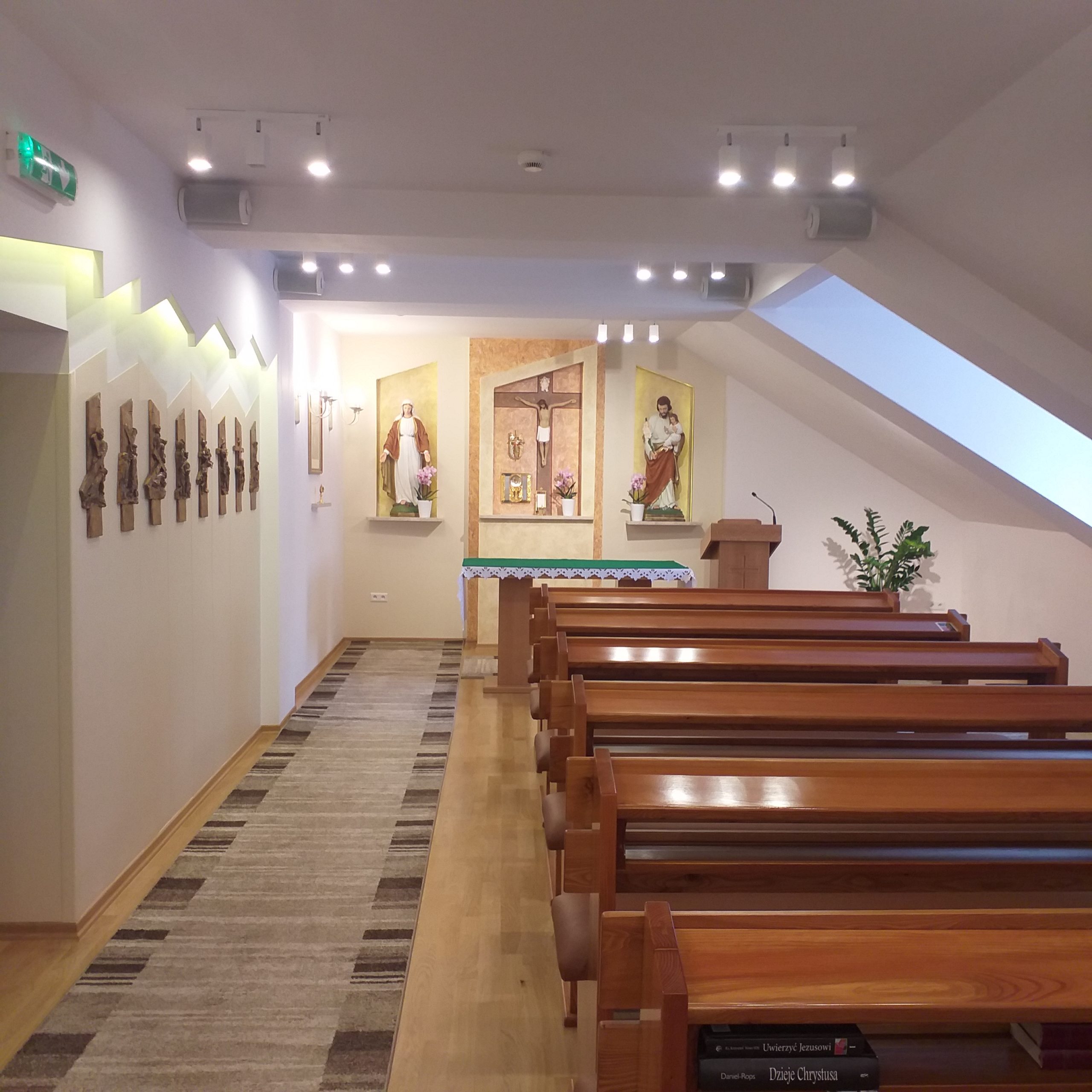 Zdjęcie kaplicy wewnątrz. Po prawej stronie rzędy drewnianych ławek. Po lewej dywan. Na samym przodzie ołtarz. 