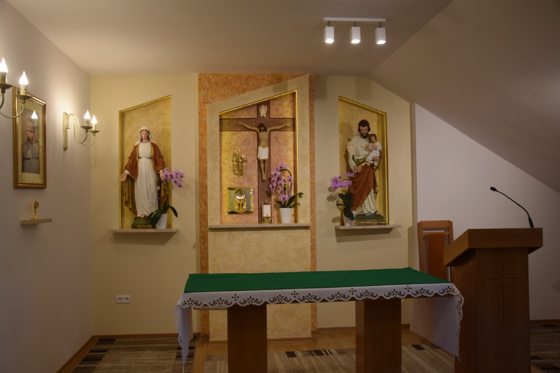 Zdjęcie kaplicy wewnątrz. Na zdjęciu ołtarz, obok niego ambona. Za ołtarzem krzyż i dwie figury. 