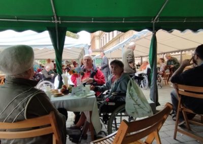 Pod parasolem siedzi grupa ludzi przy stole.