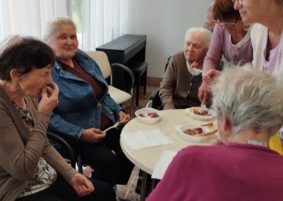 Mieszkańcy siedzą wraz z rodzinami i rozmawiają.