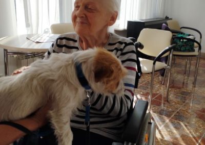 Dogoterapia- kobieta trzyma psa na kolanach