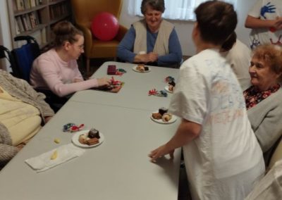 przy stole siedzą mieszkańcy DPS i spożywają ciasto