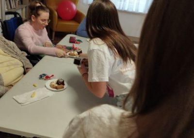 przy stole siedzą mieszkańcy DPS i spożywają ciasto