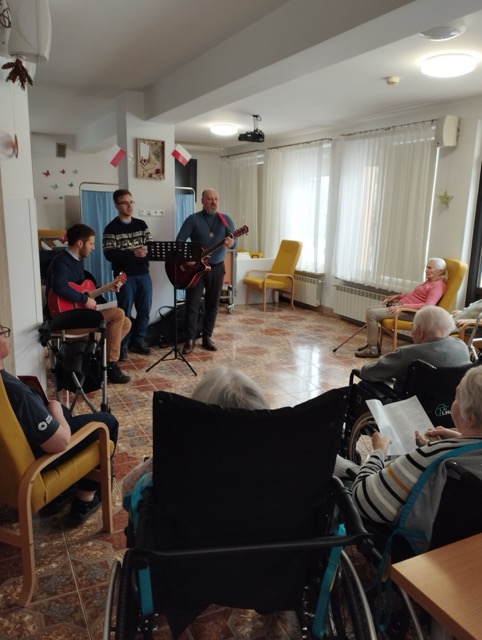 Grupa ludzi na sali słucha kolędowania