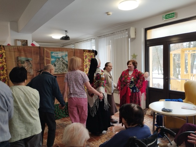 W sali grupa mieszkańców słucha występu. 